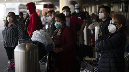 Travelers wait for a shuttle but to arrive at the Los Angeles International Airport in Los Angeles.