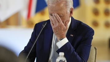 US President Joe Biden touches his face
