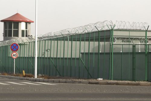 A guard tower and barbed wire fence surround a detention facility in the Kunshan Industrial Park in Artux in western China's Xinjiang region