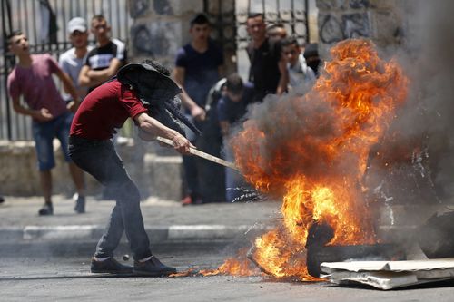A Palestinian lights a fire in the streets of Hebron. Picture: EPA