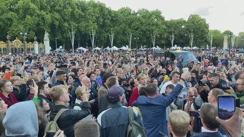 Crowd outside Buckingham Palace sing "God Save the Queen".