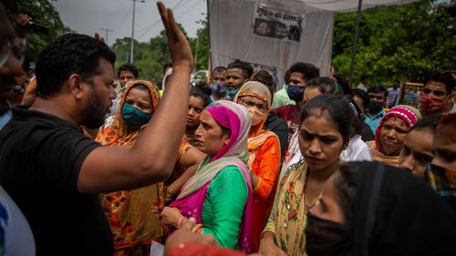 A man tries to calm protesters down as they try to block a street outside a crematorium where a 9-year-old girl from the lowest rung of India's caste system was, according to her parents and protesters, raped and killed.