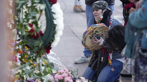 Mourners gathered outside the door of the tattoo parlour in Denver, which was one of the scenes of the shooting. 