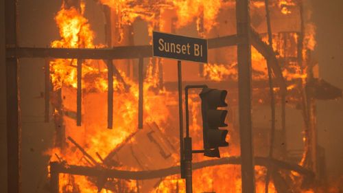 LOS ANGELES, CALIFORNIA - JANUARY 8: Flames from the Palisades Fire burn a building on Sunset Boulevard amid a powerful windstorm on January 8, 2025 in the Pacific Palisades neighborhood of Los Angeles, California. Fueled by intense Santa Ana Winds, the Palisades Fire has grown to over 15,000 acres and 30,000 people have been ordered to evacuate while a second major fire continues to burn near Eaton Canyon in Altadena. (Photo by Apu Gomes/Getty Images)