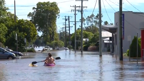 Locals kayak down River Street in Ballina to check on homes and businesses.