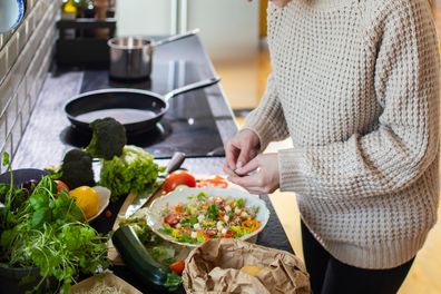 Close up of a Young adult woman preparing a healthy salad in the kitchen