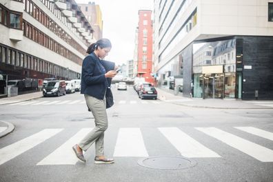 Woman using phone while crossing street