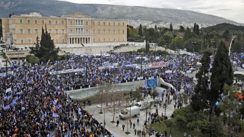Protesters wave Greek flags outside parliament in Athens, Sunday, Jan. 20, 2019.
