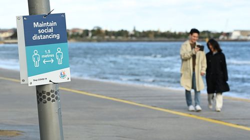 People walk along St Kilda Beach to get their daily exercise.