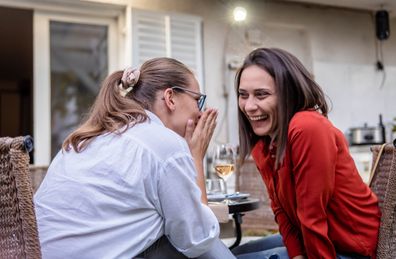 Woman whispering in friend's ear 