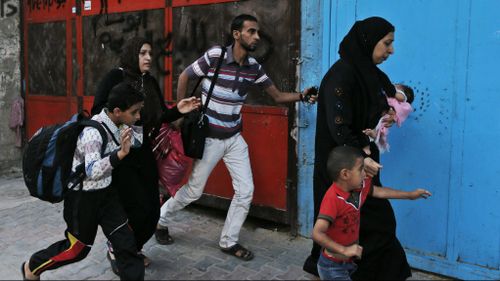 Palestinians run for shelter as they hear bombing in the distance while they flee their homes in the Shajaiyeh neighborhood of Gaza City, after Israel had airdropped leaflets warning people to leave the area, Wednesday, July 16, 2014. (AAP)