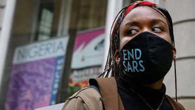 A woman wearing an "END SARS" protective face mask speaks with the police outside the Nigerian Consulate during a demonstration on October 21, 2020 in London.