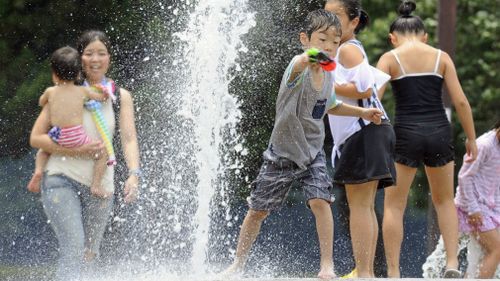 Children play at a water fountain set up at a park in Nagoya