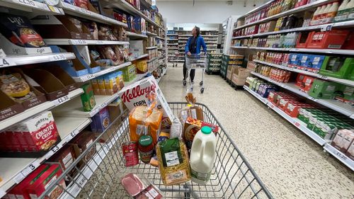 Trolley in supermarket carrying different food items.