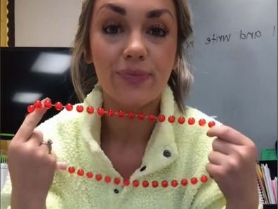 Teacher showing her red necklace to the camera