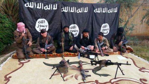 Bilardi poses with other fighters infront of an ISIL flag.