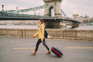 Smiling woman pulling a suitcase and enjoying Budapest