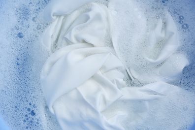 White clothing in suds, top view. Hand washing laundry