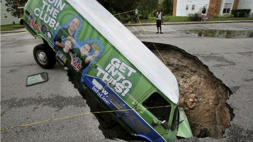A van remains in a sinkhole, Monday, Sept. 11, 2017, that opened up at the Astor Park apartment complex in Winter Springs, Fla., during Hurricane Irma's passing through central Florida. (AAP)