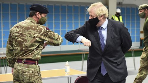 Britain's Prime Minister Boris Johnson elbow bumps a member of the military as he meets troops setting up a vaccination centre in the Castlemilk district of Glasgow, on his one day visit to Scotland, Thursday, Jan. 28, 2021.