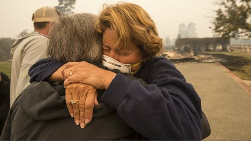  Kim Graves, left, hugs her neighbor Susan Gaynard after they both lost homes during a wildfire in Sonoma County. (AAP)