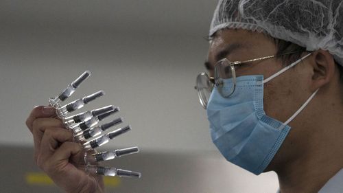 An employee manually inspects syringes of the SARS CoV-2 Vaccine for COVID-19 produced by SinoVac at its factory in Beijing on Thursday, Sept. 24, 2020