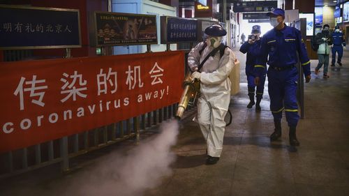 A female Chinese volunteer from Blue Sky Rescue wears a protective suit as she fumigates and disinfects an area of a local bus station in Beijing, China. 