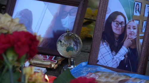 A candle, flowers and portraits of victims of the shooting are displayed on a table outside the Perm State University following a campus shooting.