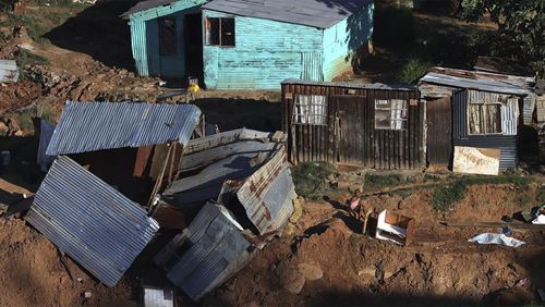 A young girl sits next to a damaged shack at an informal settlement in Durban, South Africa, Thursday, April 14, 2022.