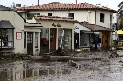 Debris and mud cover the street in front of local area shops after heavy rain brought flash flooding on Tuesday. (AAP)