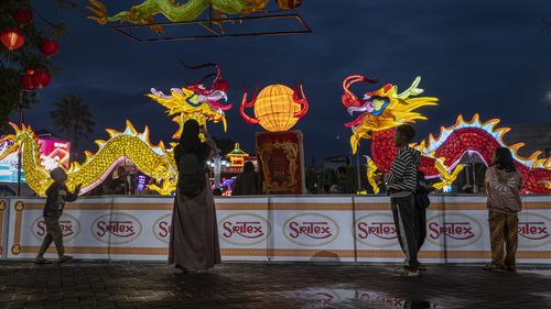 People taking pictures in front of dragon lanterns 