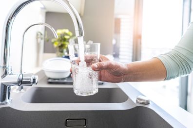 Close up of a woman hand filling a glass of water directly from the tap.