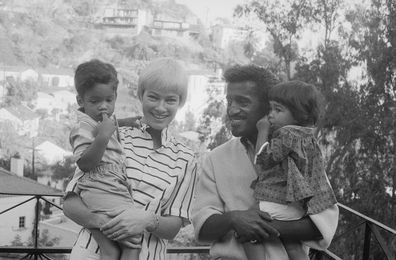 Sammy Davis, Jr., and his wife, actress May Britt, pose with their adopted son Mark Sidney Davis (left). Sammy holds their 16-month-old daughter, Tracey. 