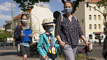 Juliane and her son Paul, 7, and daughter Sarah, 12, wear protective face masks while walking in Baumschulenweg district and working on a school project to map the types of businesses in the street during the coronavirus crisis on April 27, 2020 in Berlin, Germany. 