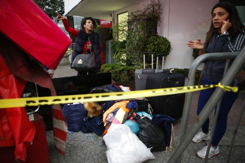 A young woman stands on a street corner with her belongings after having to abandon her earthquake damaged apartment building, in the Roma neighbourhood. (AP)