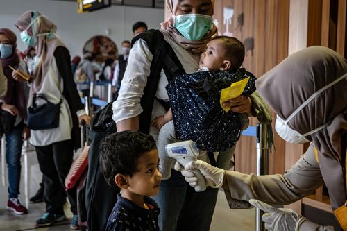 An Indonesian health official checks the temperatures of a boy as they pass a thermal scanner monitor upon arrival at the Adisucipto International Airport on March 5 in Yogyakarta.