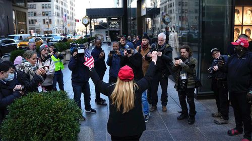 Un protestatar singuratic în fața Turnului Trump, înconjurat de mass-media.