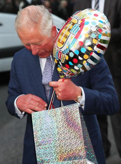 The Prince of Wales holds a birthday gift as he arrives for a tea party at Spencer House in London to celebrate 70 inspirational people marking their 70th birthday.