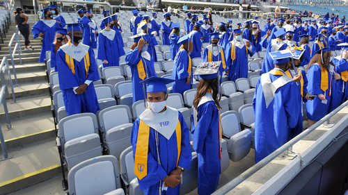 Graduates of the Frank H. Peterson Academies of Technology stand as classmates file in to their socially distanced seats at the start of Friday morning's graduation ceremony in TIAA Bank Field. 