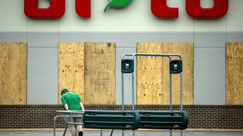 A butcher at the BiLo grocery store, moves a shopping cart return rack during storm preparations for Hurricane Matthew. (AAP)