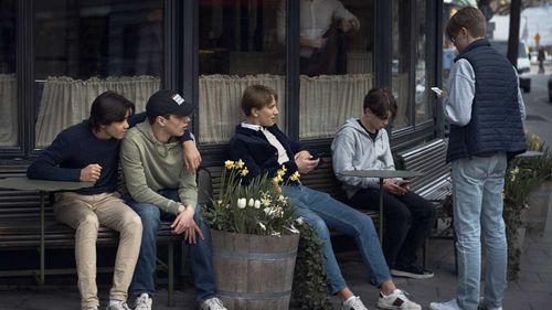 Youth hang out outside a restaurant in Stockholm, Sweden. Social distancing is recommended but not enforced in the country.