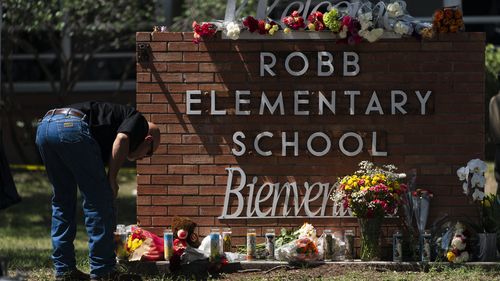A law enforcement personnel lights a candle outside Robb Elementary School in Uvalde, Texas.