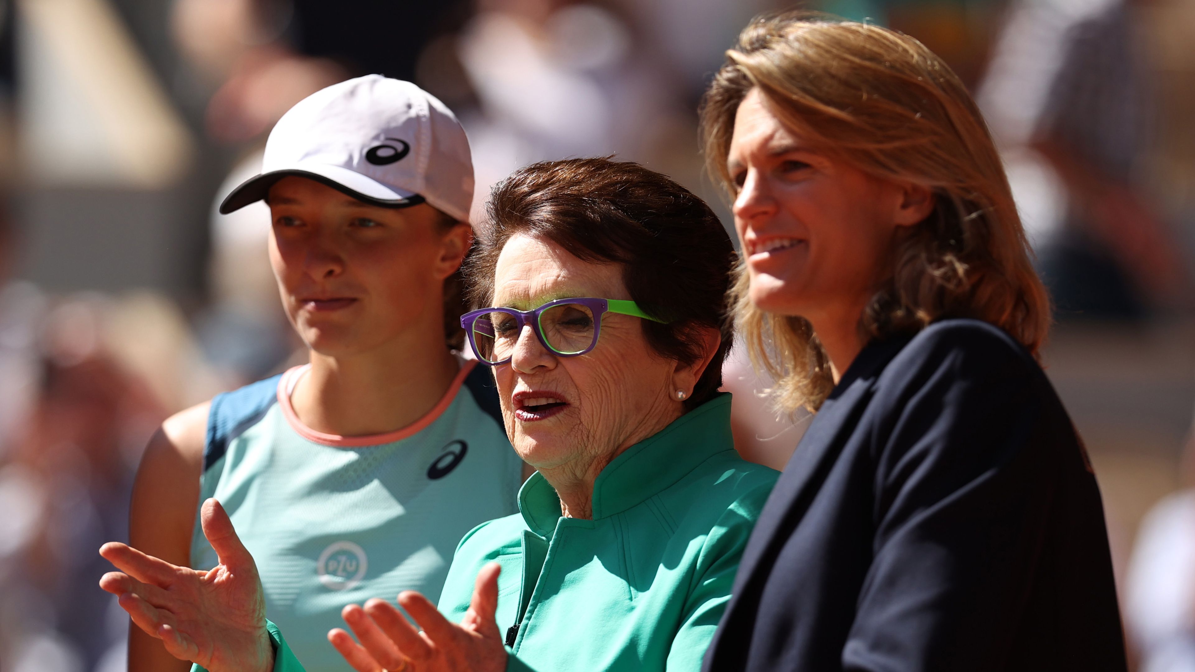 Iga Swiatek and Amelie Mauresmo stand in tribute to Billie Jean King on the 50th Anniversary of her Roland Garros Triumph.