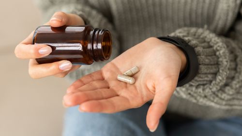 Em close up as mãos da jovem segurando cápsulas de ervas remédios, cortadas de senhora tomando suplementos produtos ou cápsula do tipo vitamina. Nutrição para mulheres, saúde, drogas