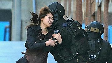 Jieun Bae runs to armed tactical response police officers for safety after she escaped from a cafe under siege at Martin Place in the central business district of Sydney, Australia. (Rob Griffith)