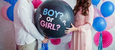 Parents holding boy or girl balloon. Gender reveal party.