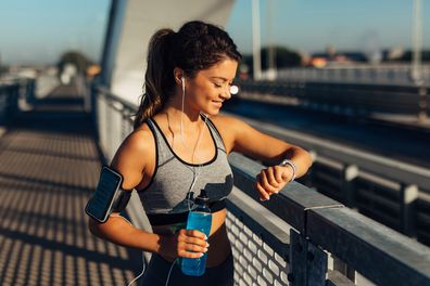 Female runner taking a break from running workout and reviewing info on her smart watch.