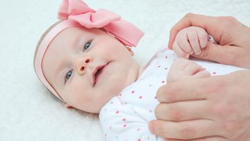 Adorable Baby Girl with Pink Hair Band and Mother Hands