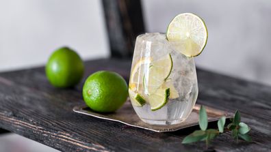 Cold cocktail with lime, lemon, tonic, vodka and ice on vintage background