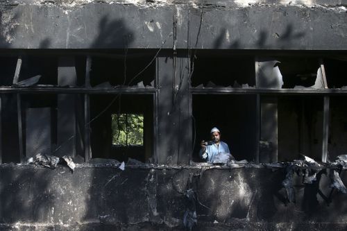 مردی با تلفن همراه خود در داخل ساختمان رادیو پاکستان که در درگیری روز چهارشنبه بین پلیس و حامیان عمران خان نخست وزیر سابق پاکستان در پیشاور پاکستان سوخته بود، عکس می گیرد، پنجشنبه 11 می 2023. 